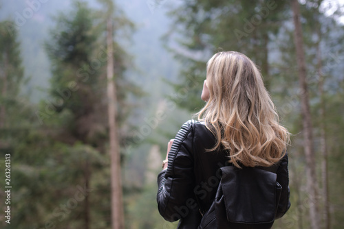 Blonde caucasian girl looking the forest landscape during her adventure travel in the mountains © Nicola
