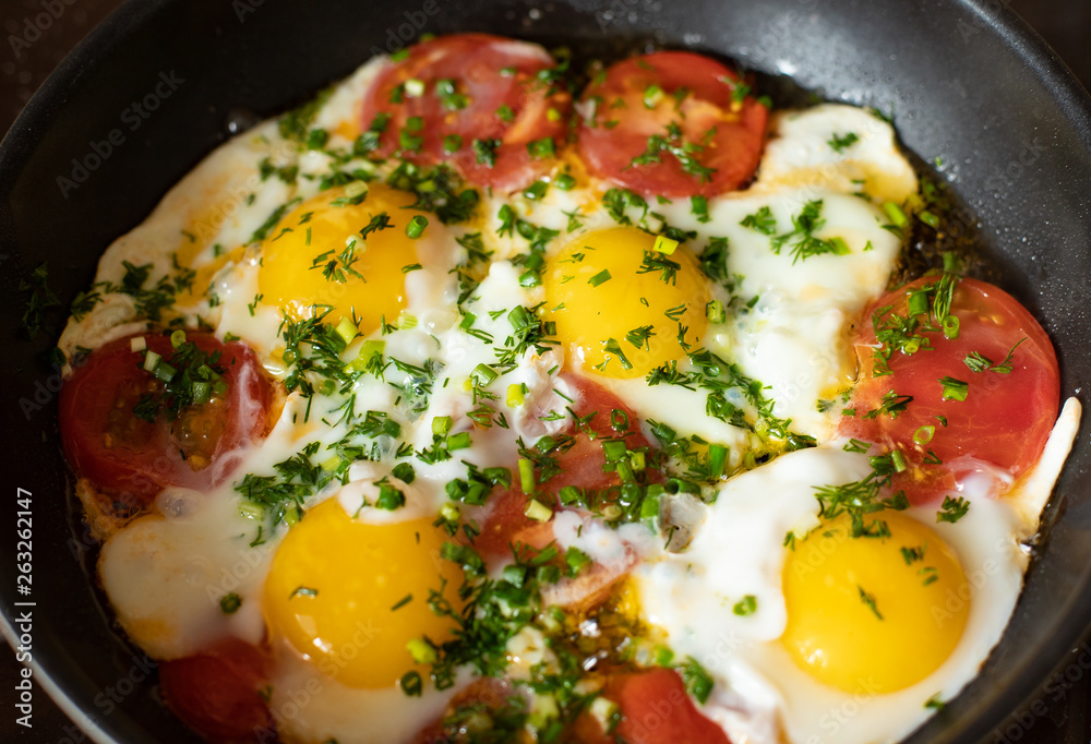 Fried eggs in a pan with tomatoes and herbs for Breakfast close-up Fried eggs in a pan with tomatoes and herbs for Breakfast close-up