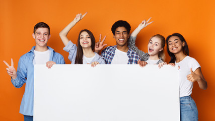 Happy friends holding empty banner, orange background