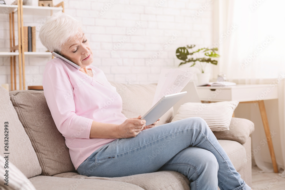 Busy senior woman consulting client on phone and reading contract Busy senior woman consulting client on phone and reading contract
