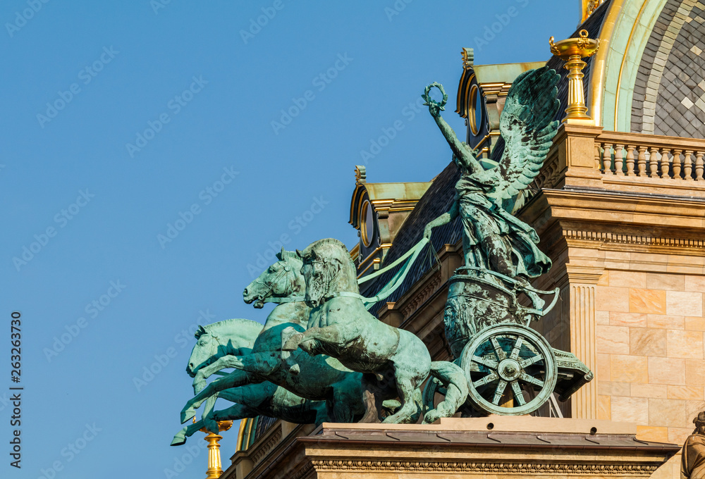 Bronze three horse chariot on top of Prague National Theater during sunset