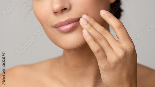 Woman applying lip balm over grey background