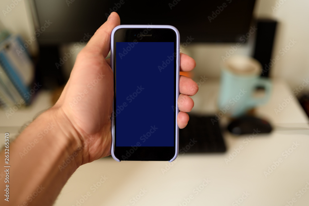 Male hand with a smartphone. Black blank screen. Home background