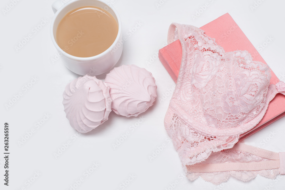 Obraz premium Cup of coffee with marshmallows. Pink lace bodice and notepad on white background. Fashionable concept.
