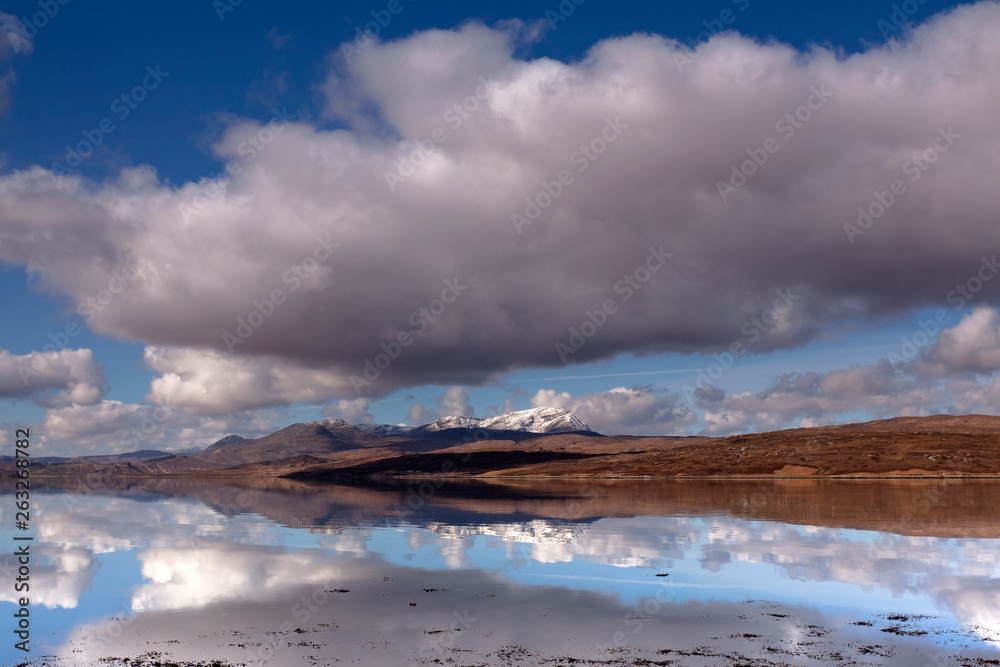 Snow white peaks enfold by lovely cloudscape and reflections