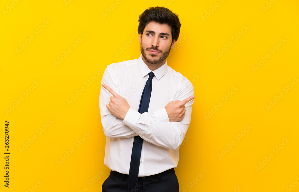 Businessman on isolated yellow background pointing to the laterals having doubts Businessman on isolated yellow background pointing to the laterals having doubts