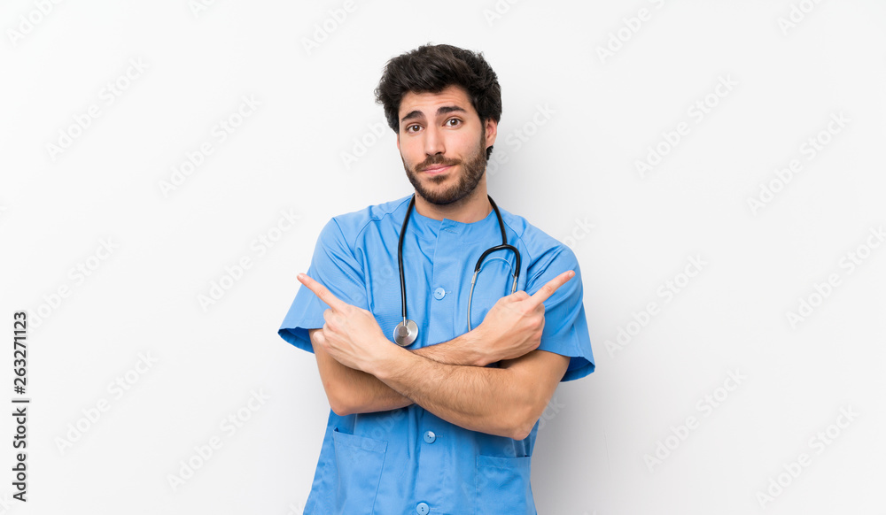 Surgeon doctor man over isolated white wall pointing to the laterals having doubts Surgeon doctor man over isolated white wall pointing to the laterals having doubts