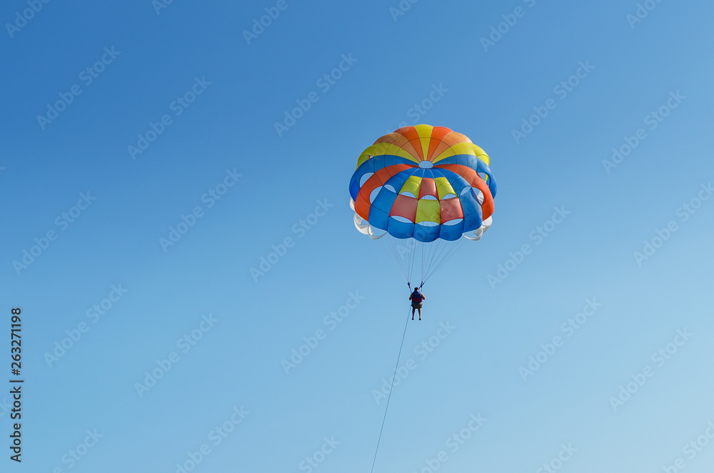 Parasailing is an extreme sport, people fly by parachute against the blue sky Parasailing is an extreme sport, people fly by parachute against the blue sky