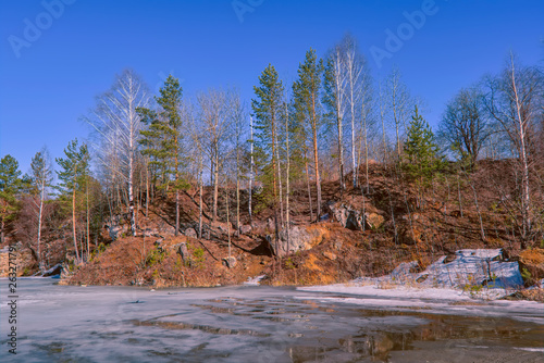 Early spring ice melts on a forest lake.