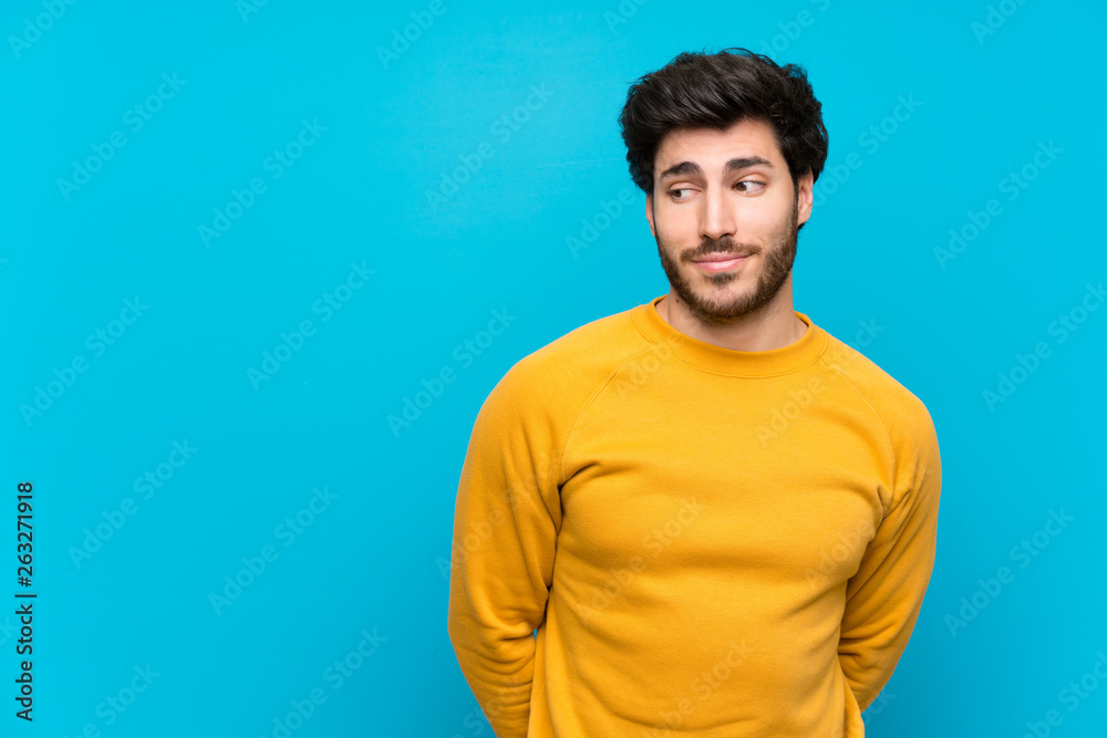 Handsome over isolated blue wall making doubts gesture looking side Handsome over isolated blue wall making doubts gesture looking side