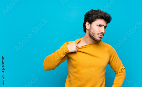 Handsome over isolated blue wall with tired and sick expression