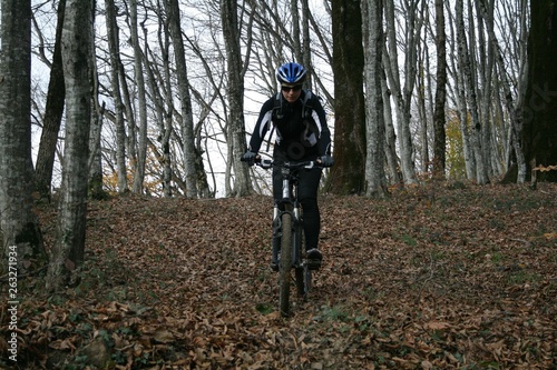 A young woman riding a bike on a trail in the woods.