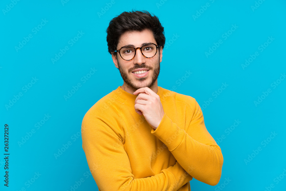 Handsome over isolated blue wall with glasses and smiling Handsome over isolated blue wall with glasses and smiling