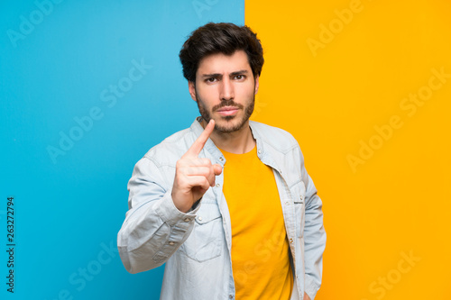 Handsome over isolated colorful background frustrated and pointing to the front