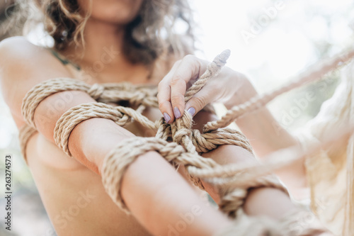 Woman bound with a rope in Japanese technique shibari outdoors