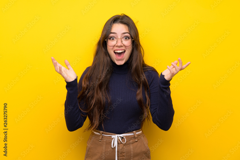 Teenager girl over isolated yellow wall smiling a lot Teenager girl over isolated yellow wall smiling a lot