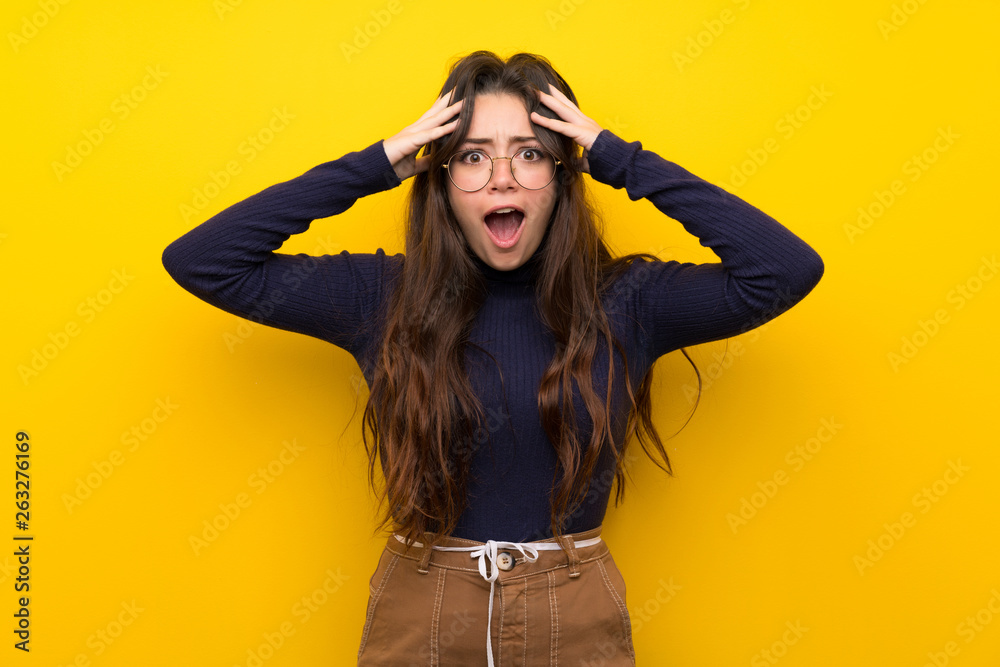 Teenager girl over isolated yellow wall with surprise expression Teenager girl over isolated yellow wall with surprise expression