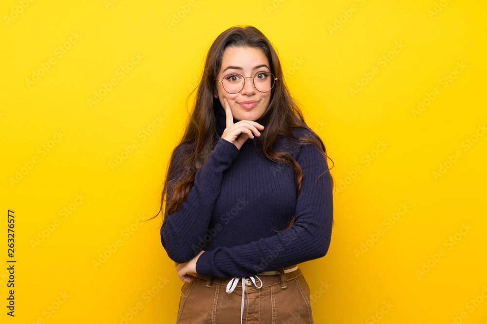 Teenager girl over isolated yellow wall Looking front Teenager girl over isolated yellow wall Looking front