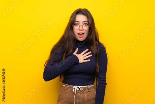 Teenager girl over isolated yellow wall surprised and shocked while looking right © luismolinero