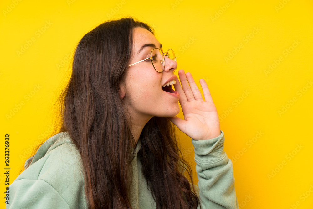 Teenager girl with sweatshirt shouting with mouth wide open Teenager girl with sweatshirt shouting with mouth wide open
