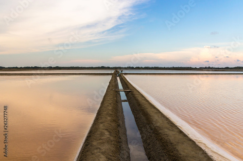 Salt farm with beautiful reflection of nature at sunset time in Na Klua - baan laem, Petchaburi,Thailand. Salt production is made from sea water and sunlight until dry into crystal. photo