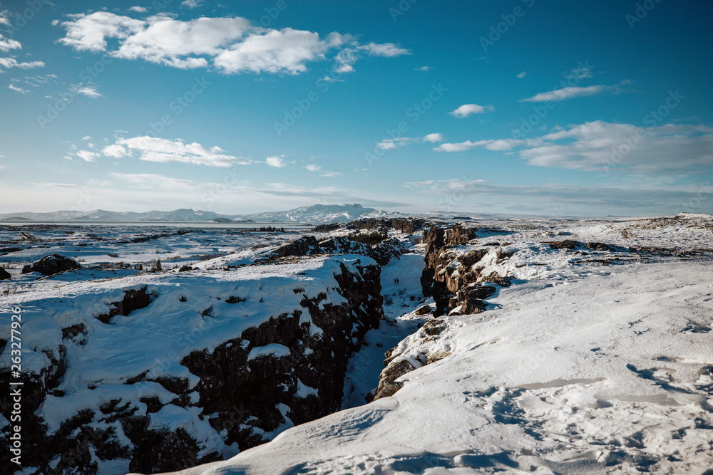 beautiful canyon in Iceland covered in snow with a blue sky and clouds