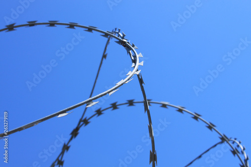 Barbed wire on fence with blue sky, the concept of prison, salvation, copy space.