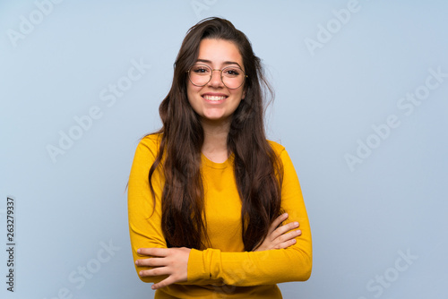 Teenager girl over isolated blue wall laughing