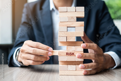 Businessman hand placing or pulling wooden block on the tower. Business planning, Risk Management, Solution and strategy Concepts