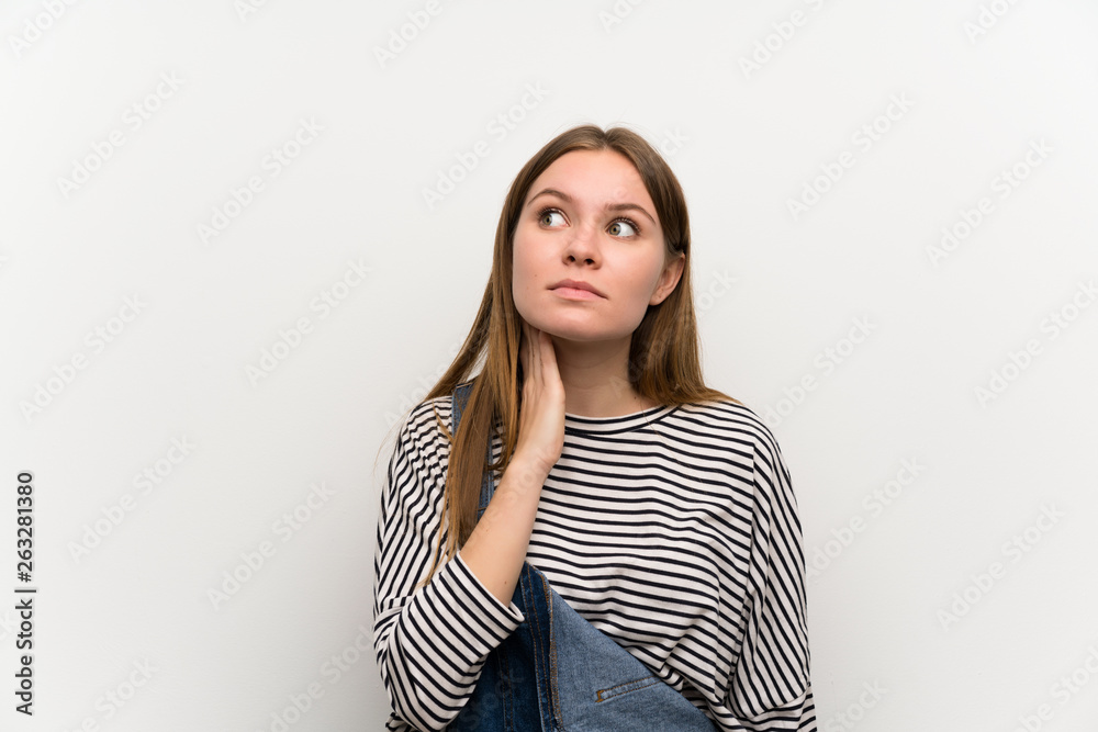 Young woman in dungarees over white wall standing and thinking an idea Young woman in dungarees over white wall standing and thinking an idea