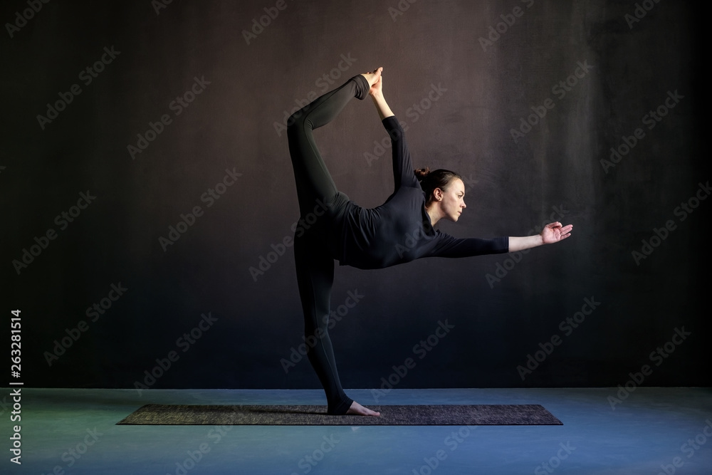 Woman practicing yoga, stretching in Natarajasana exercise Woman practicing yoga, stretching in Natarajasana exercise