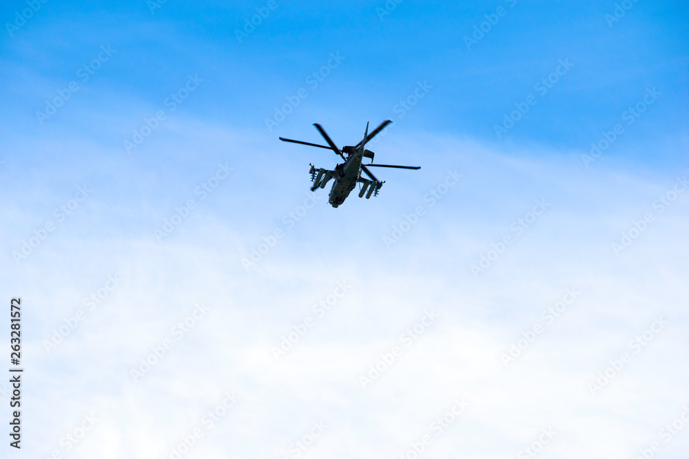 Russian military combat attack helicopter K-52 Alligator flies against a blue sky and clouds Russian military combat attack helicopter K-52 Alligator flies against a blue sky and clouds