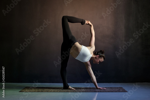 Young caucasian slim yoga girl doing variation of adho mukha shvanasana.