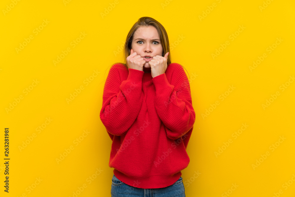 Young woman over yellow wall nervous and scared putting hands to mouth Young woman over yellow wall nervous and scared putting hands to mouth