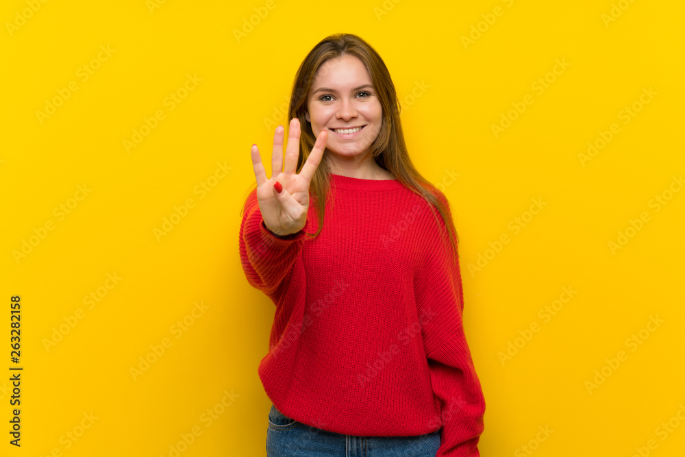Young woman over yellow wall happy and counting four with fingers Young woman over yellow wall happy and counting four with fingers
