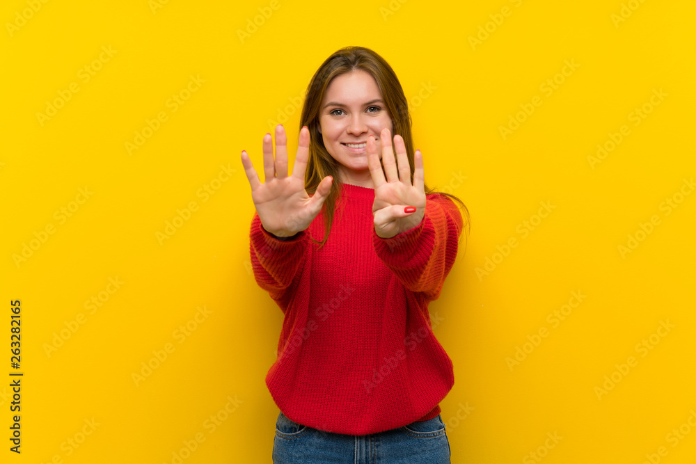 Young woman over yellow wall counting nine with fingers Young woman over yellow wall counting nine with fingers