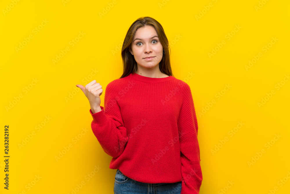 Young woman over yellow wall pointing to the side to present a product Young woman over yellow wall pointing to the side to present a product