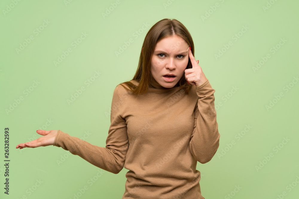 Young woman with turtleneck sweater making the gesture of madness putting finger on the head Young woman with turtleneck sweater making the gesture of madness putting finger on the head