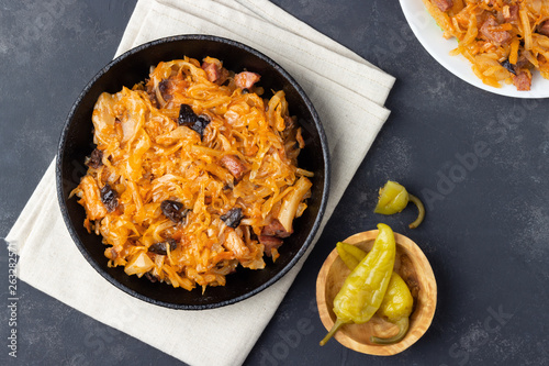 Traditional dish of polish cuisine - Bigos from fresh cabbage, meat and prunes. Top view. Dark background. photo