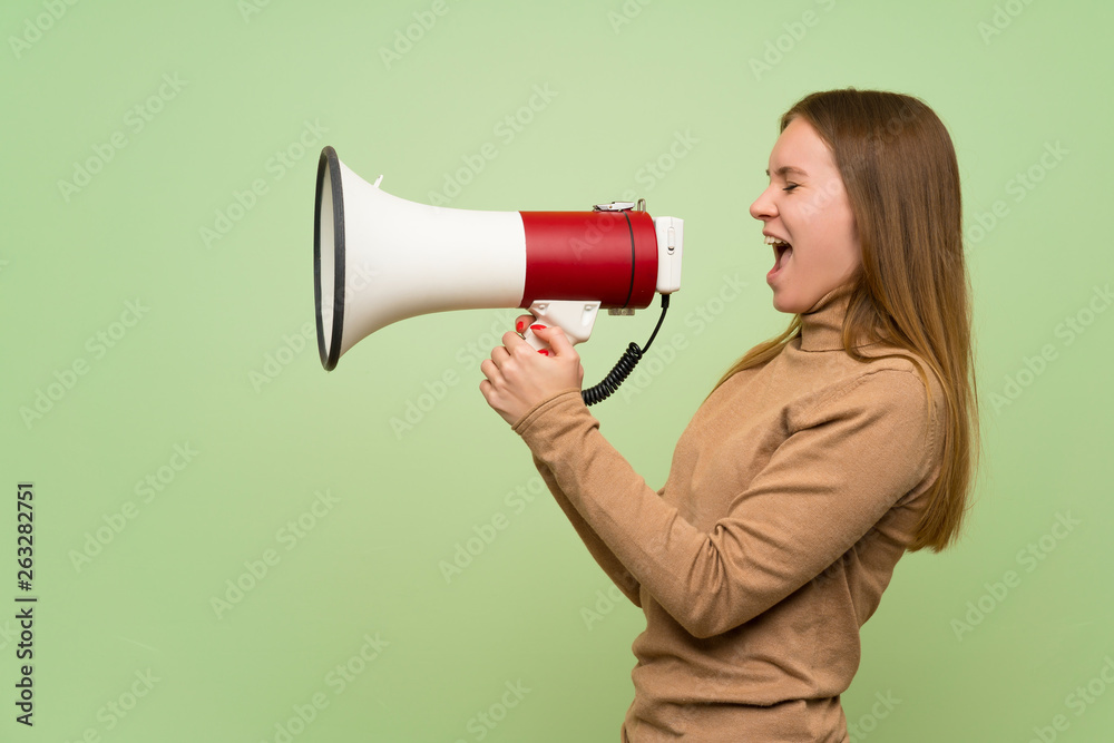 Young woman with turtleneck sweater shouting through a megaphone Young woman with turtleneck sweater shouting through a megaphone