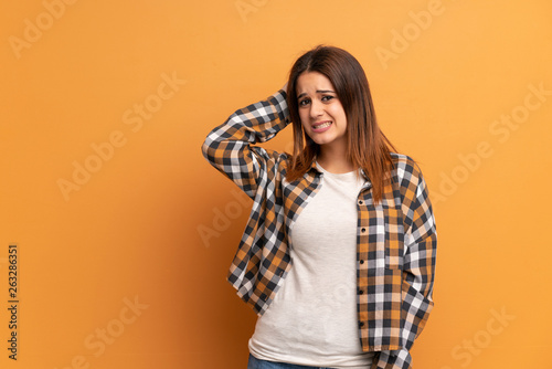 Young woman over brown wall having doubts