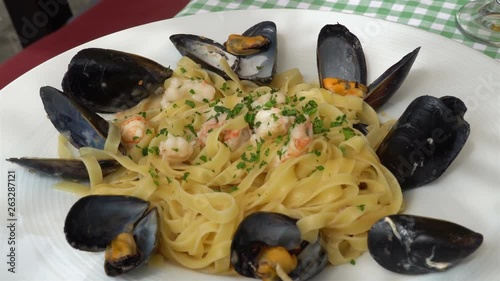 Traditional mediterranean pasta with mussels and seafood on a traditional Mediterranean plate garnished with summer vegetables and fruits - greece, croatia, italy, montenegro, squid.