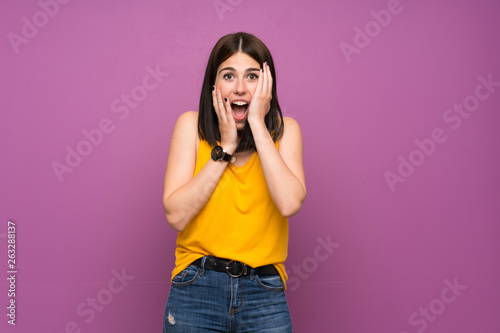 Young woman over isolated purple wall with surprise and shocked facial expression
