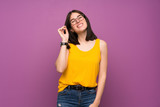 Young woman over isolated purple wall with glasses and happy