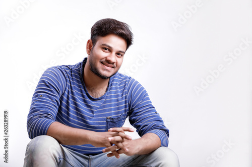 Handsome young Indian man siting on table isolated over white background photo