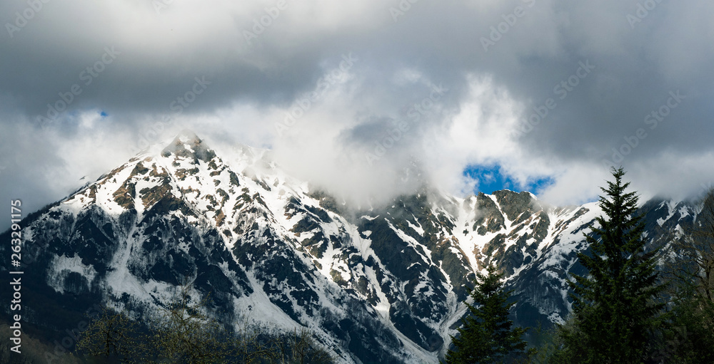 Panoramic view of snowy mountains ridge in clouds