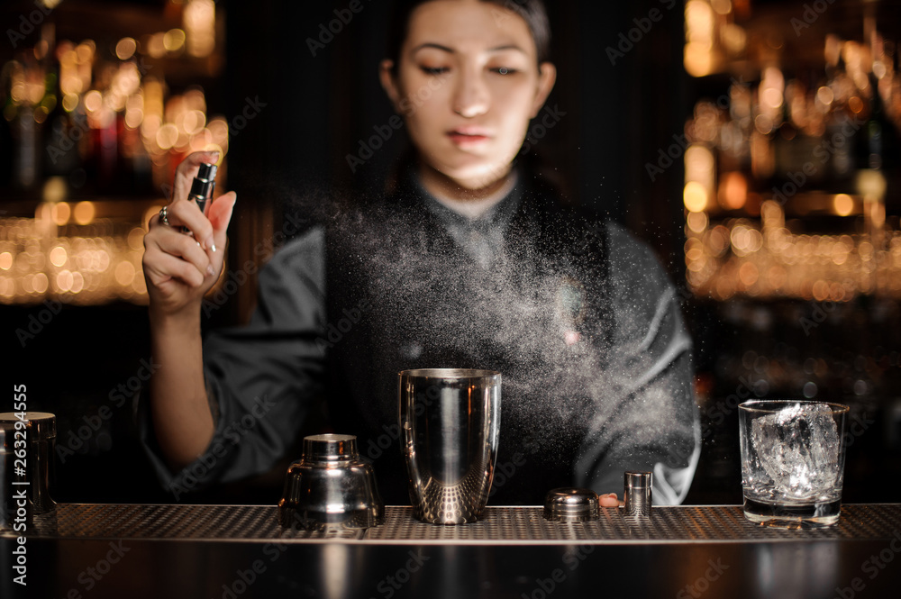 Portrait of bartender pouring cocktail with shaker and sprayer