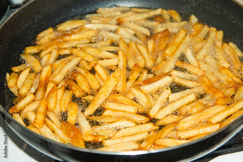 Fried french fries in a pan in sunflower oil.