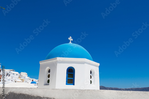 Santorini, Greece - July 07, 2017: Blue dome of church close-up in island Santorini. Background white houses and blue sea.