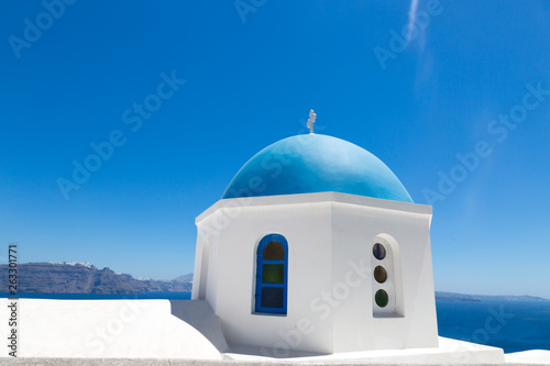 Santorini, Greece - July 07, 2017: Blue dome of orthodox church close-up in island Santorini. Background white houses and blue sea.